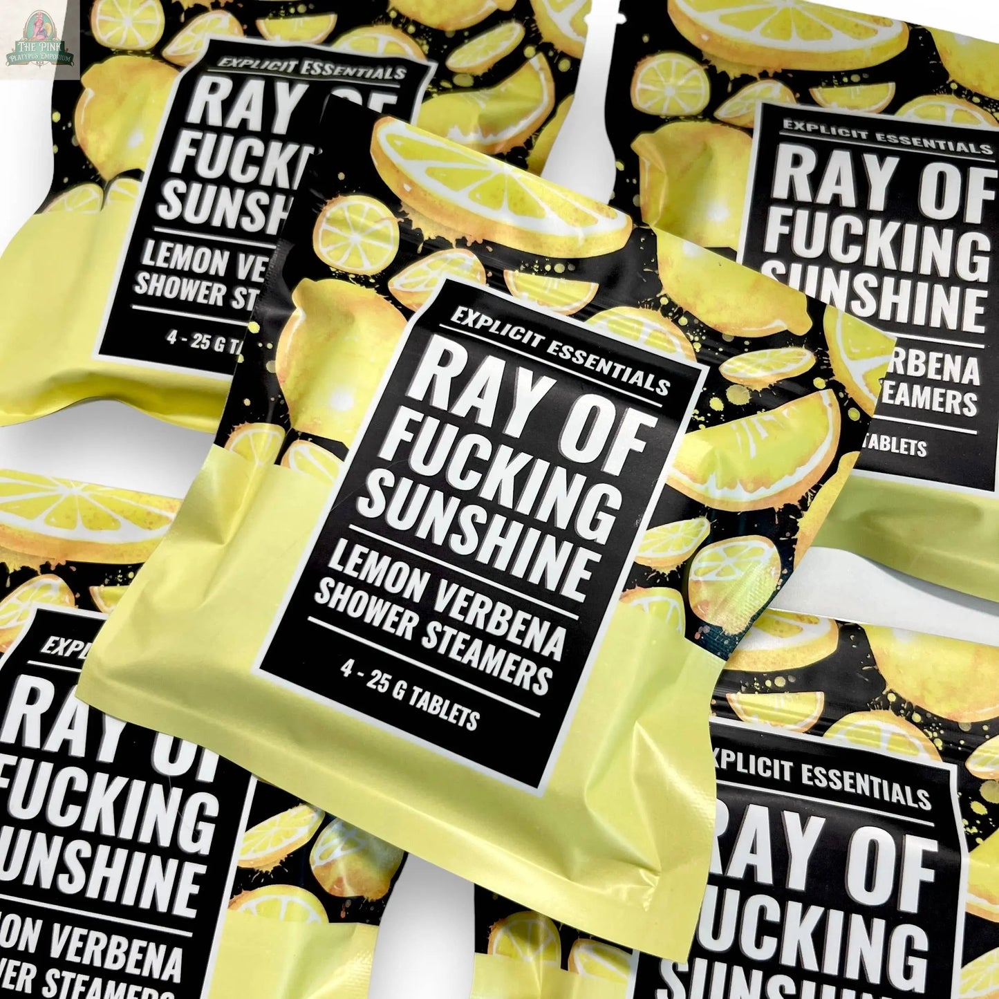 Several yellow and black Ray of F&cking Sunshine Shower Steamers by Explicit Essentials are arranged overlapping, each bag showing lemon slice graphics and bold white text, enriched with essential oils.