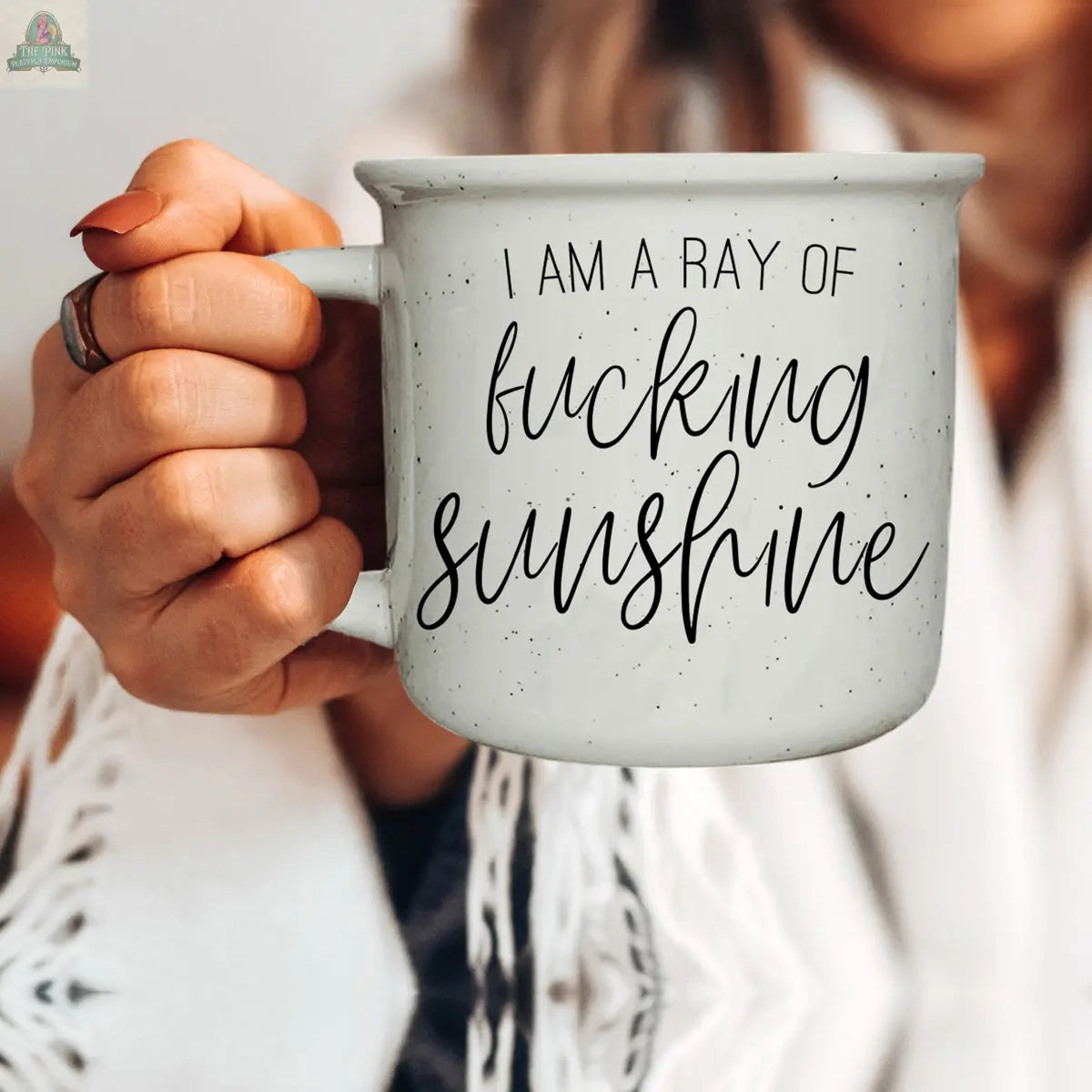 A person wearing white and a ring holds the "Ray of F'n Sunshine 14.5oz" gray ceramic mug featuring black script, making a bold, sarcastic style statement.