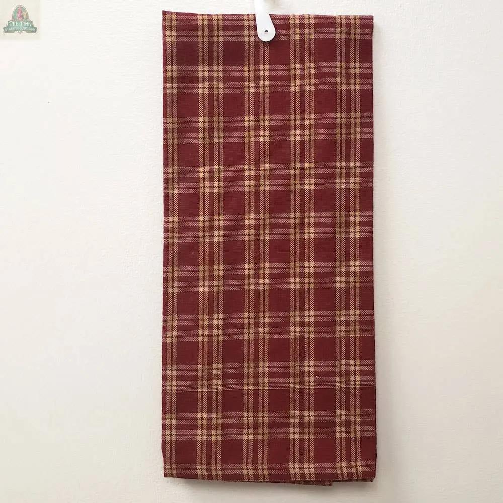 The Red Kitchen Towel With Tan Lines, made of cotton and measuring 15 x 25 inches, is neatly folded and hanging on a white wall from a white plastic hook.