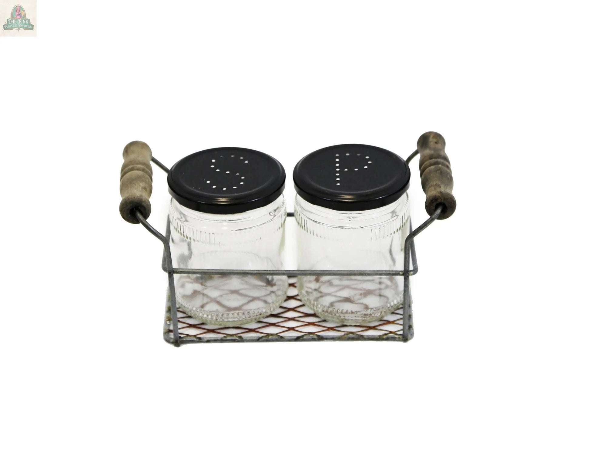 The Rusty Zinc Two Jar Caddy With Jars features two glass jars with black “S” and “P” lids in a wire basket with wooden handles, making it a stylish decorative accent for any tabletop.