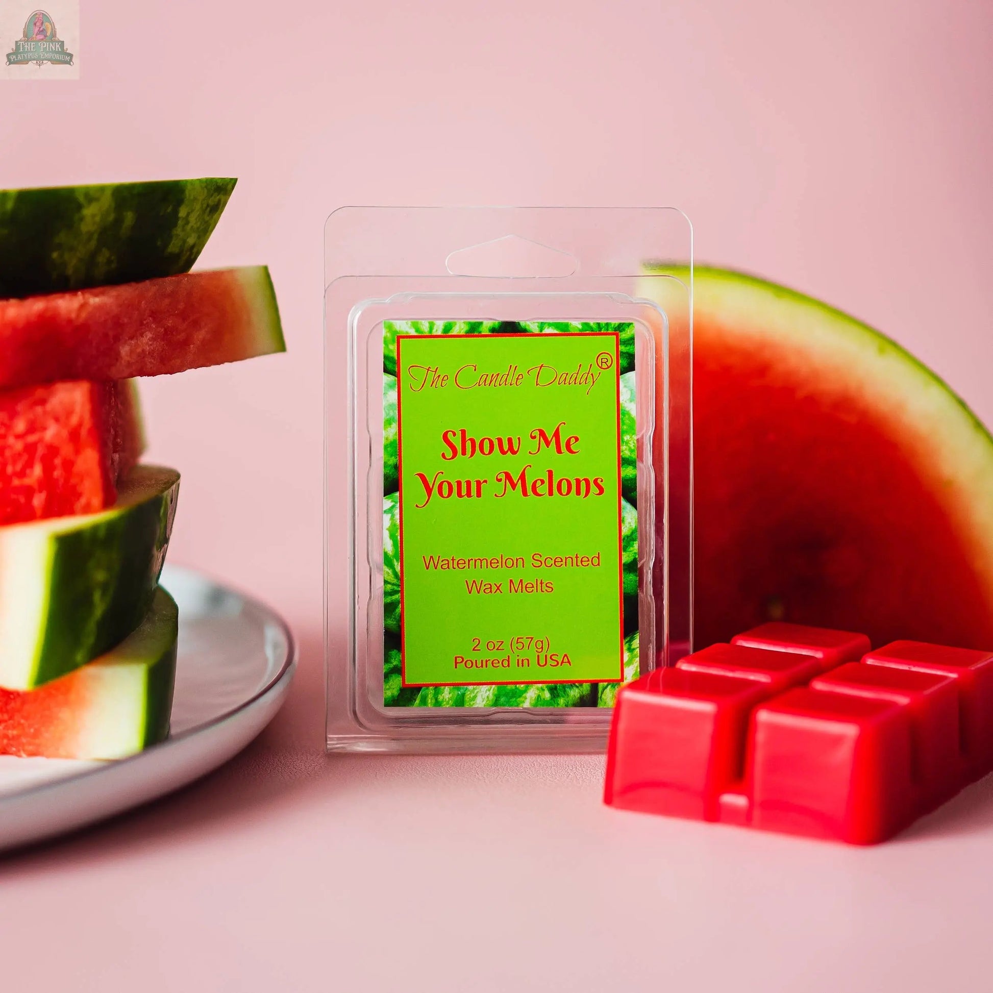 A package of SHOW ME YOUR MELONS - RIPE JUICY WATERMELON SCENTED MELT rests on a pink surface with watermelon slices and red wax cubes, against a pink background. Perfect for adding a sweet, fruity touch to your space.
