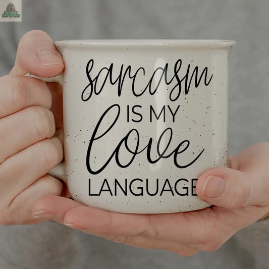 A person holds the Sarcasm Love 14.5oz mug—a white speckled ceramic mug with black script saying "Sarcasm is my love language"—while wearing a gray top and showing off their favorite mug.