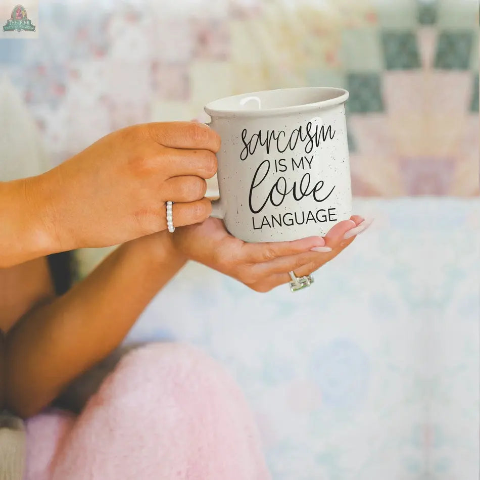 A person with manicured nails and rings holds the Sarcasm Love 14.5oz mug, which reads “Sarcasm is my love language,” against a soft pastel background.