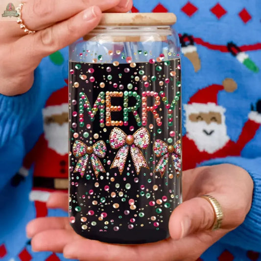 Wearing a festive blue sweater, a person holds the Sequin MERRY holiday glass tumbler, adorned with colorful beads spelling "MERRY" and bow designs among pastel dots. The tumbler has a wooden lid and is cradled with both hands.