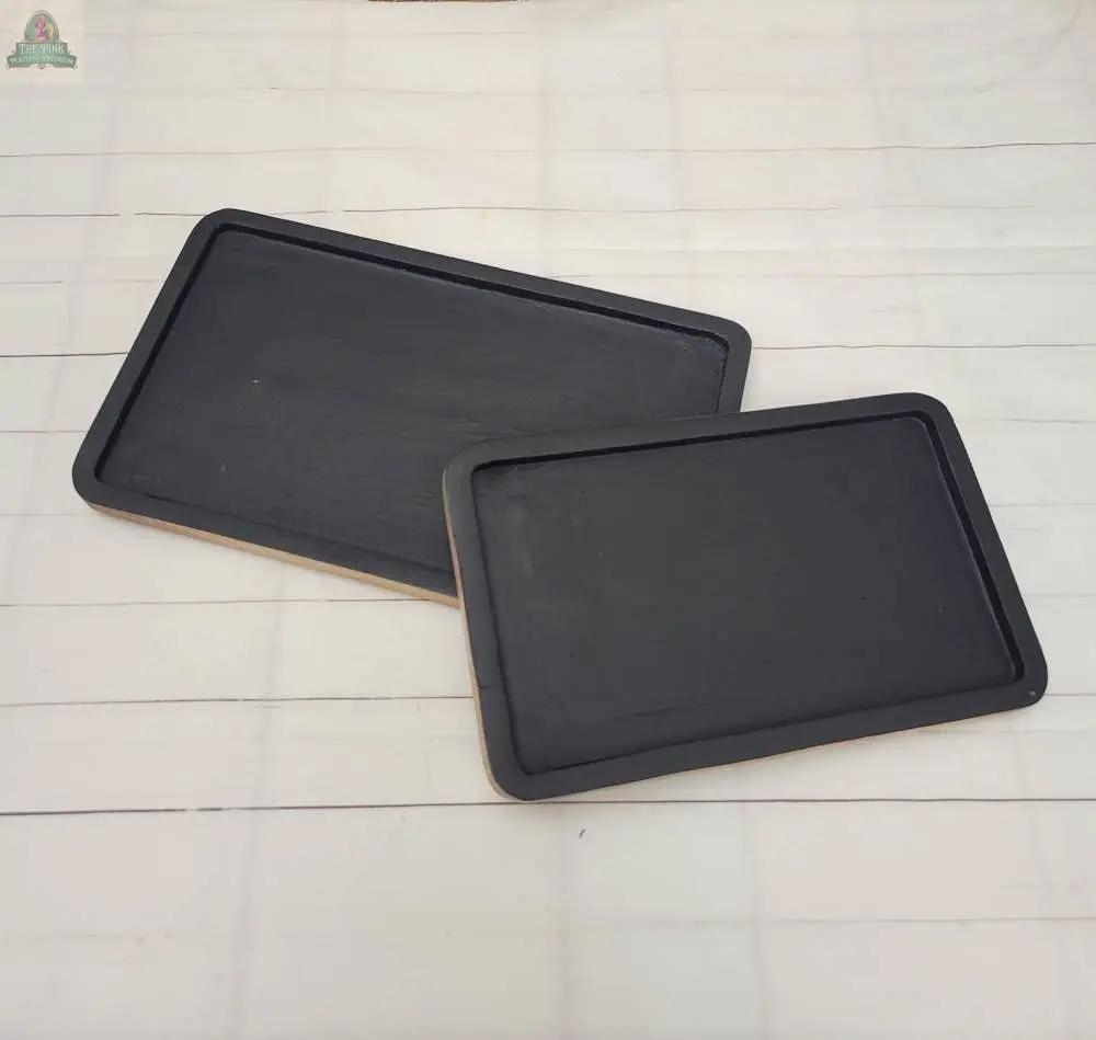 Two rectangular Wood Trays with a matte black finish and raised edges are placed on a light-colored tiled surface, overlapping slightly at one corner.