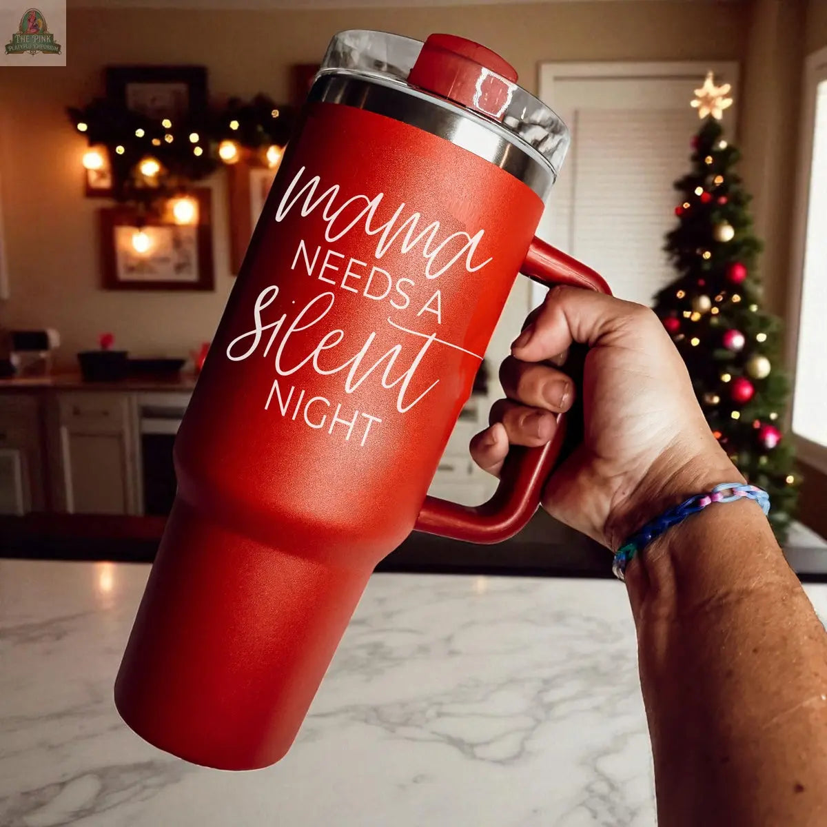 A hand holds the Silent Night 40oz tumbler with "Mama needs a silent night" printed on it. Christmas decorations in the background highlight this insulated mug as the perfect holiday gift.