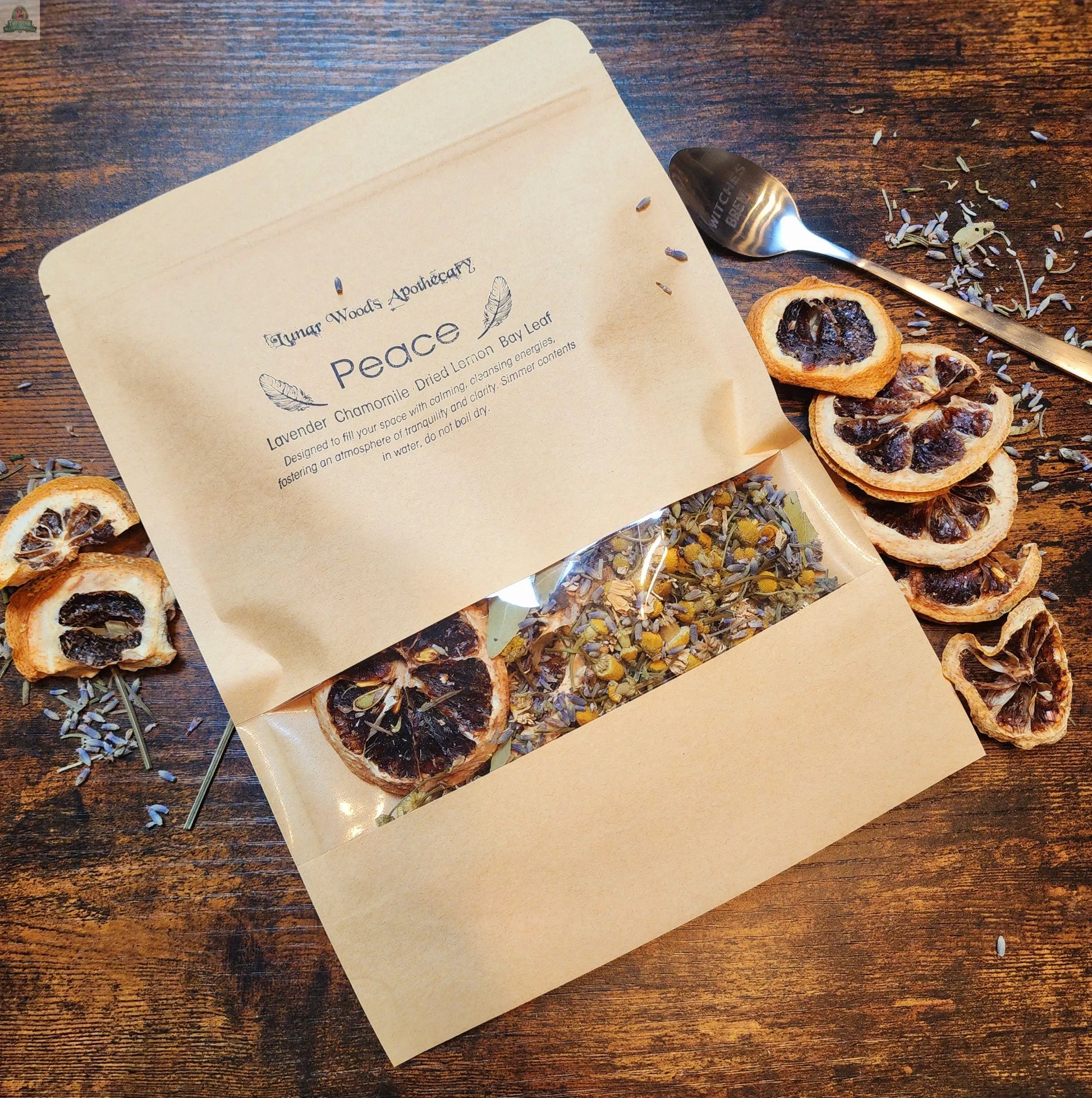 The Simmer Pot Kit- Peace comes in a brown resealable pouch and features a calming blend of dried lavender, chamomile, bay leaf, and citrus, with loose herbs displayed on a wooden surface to create a peaceful atmosphere.