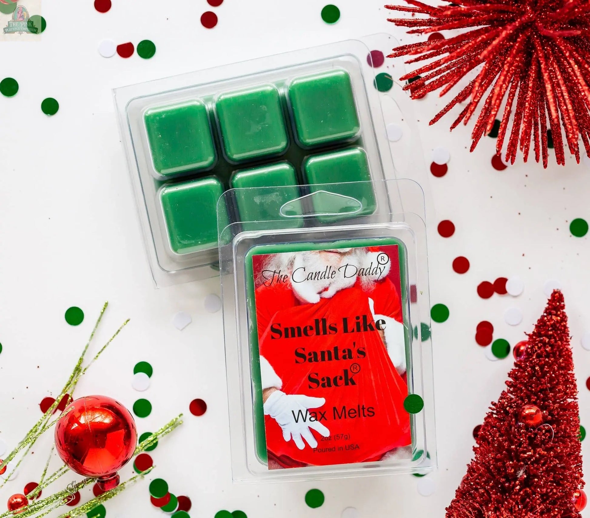A pack of Smells Like Santa’s Sack - Christmas Brown Sugar Fig wax melts sits on a white surface, surrounded by red glittery decorations, festive confetti, and a red ornament for strong-scented holiday cheer.