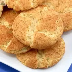 A close-up of golden-brown cookies sprinkled with cinnamon sugar on a white plate captures the inviting aroma of Snickerdoodle Atomizer Oils.