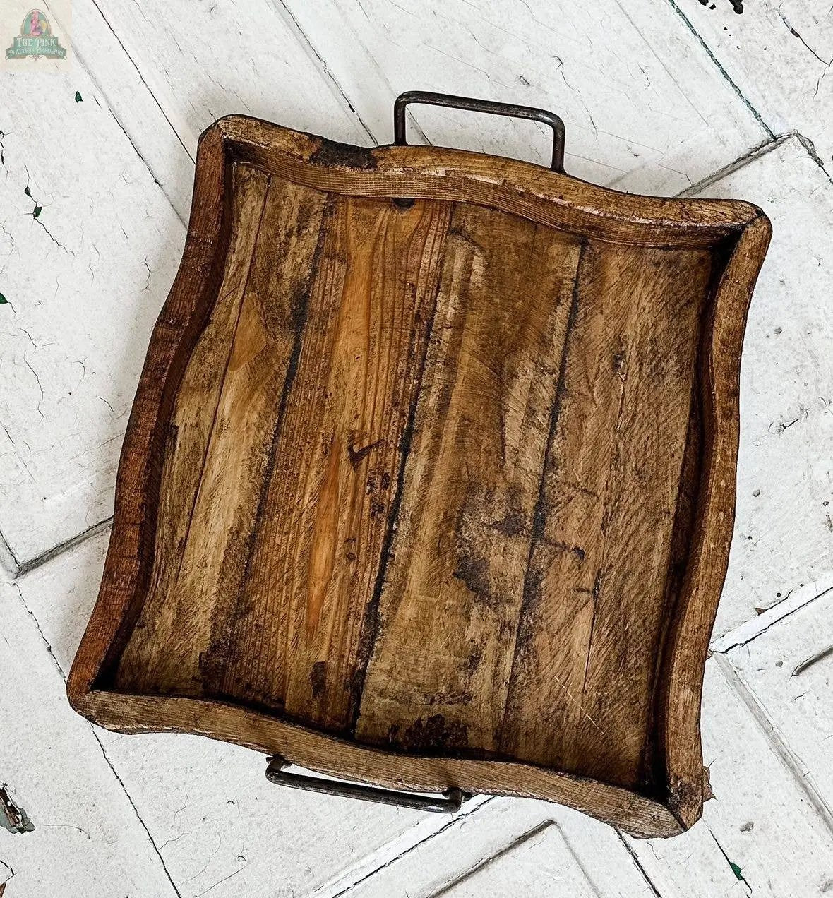 The Square Wood Tray, Natural, Handmade - 7.2 features uneven, wavy edges and two metal handles, and is displayed on a white herringbone-patterned wooden surface.