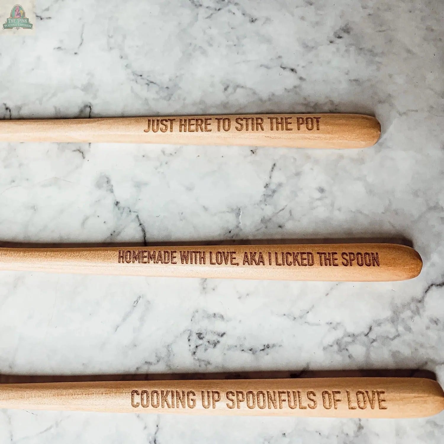 Stirring the Pot" includes three engraved wooden spoons on marble, each with a playful phrase—an ideal kitchen gift. Pair them with a porcelain spoon rest for a clean, stylish countertop.