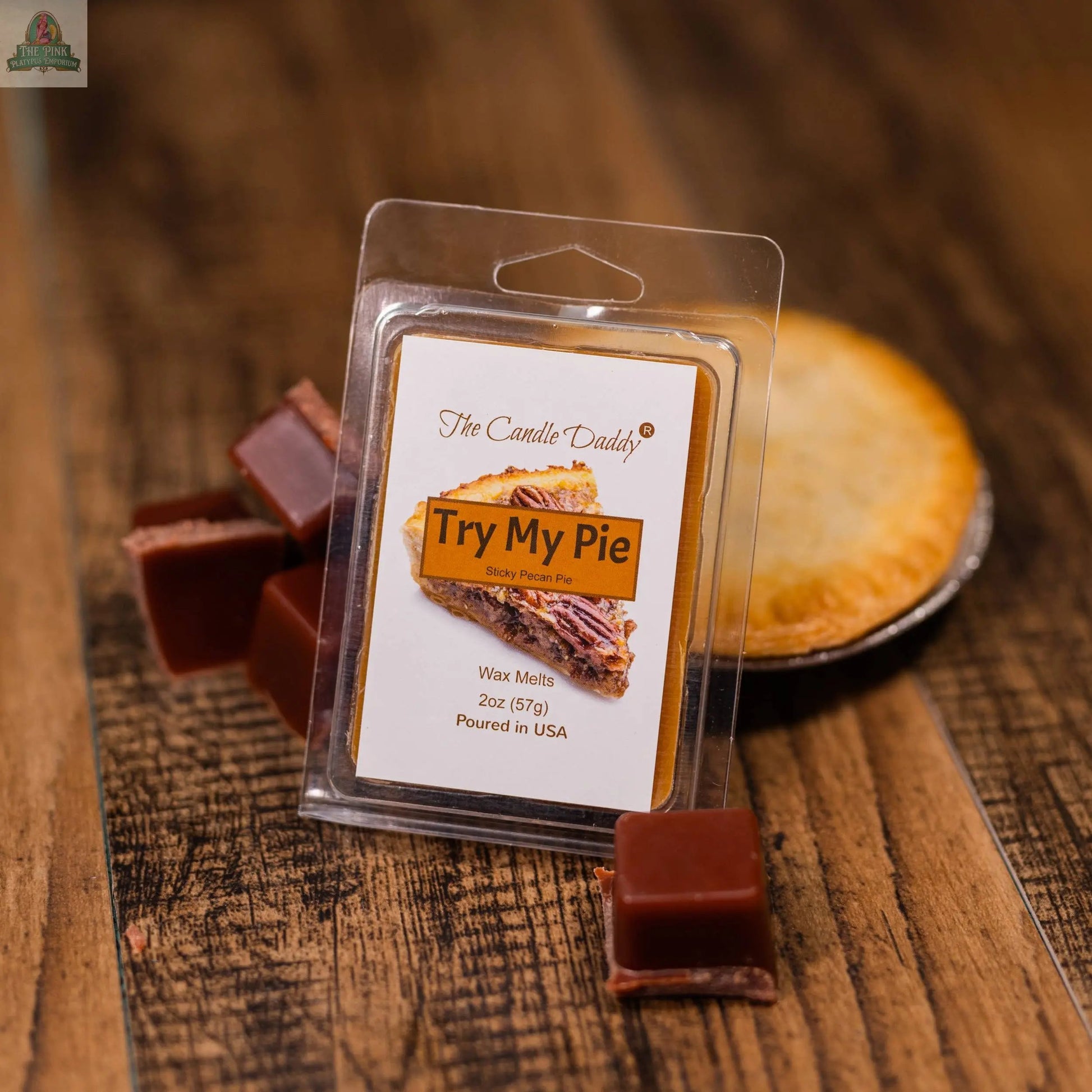 A pack of TRY MY PIE - STICKY PECAN PIE SCENTED WAX MELT - 1 PACK by The Candle Daddy sits on a wooden surface with caramel pieces and a whole pie nearby, ideal for aromatherapy and adding a delicious pecan pie scent to your space.