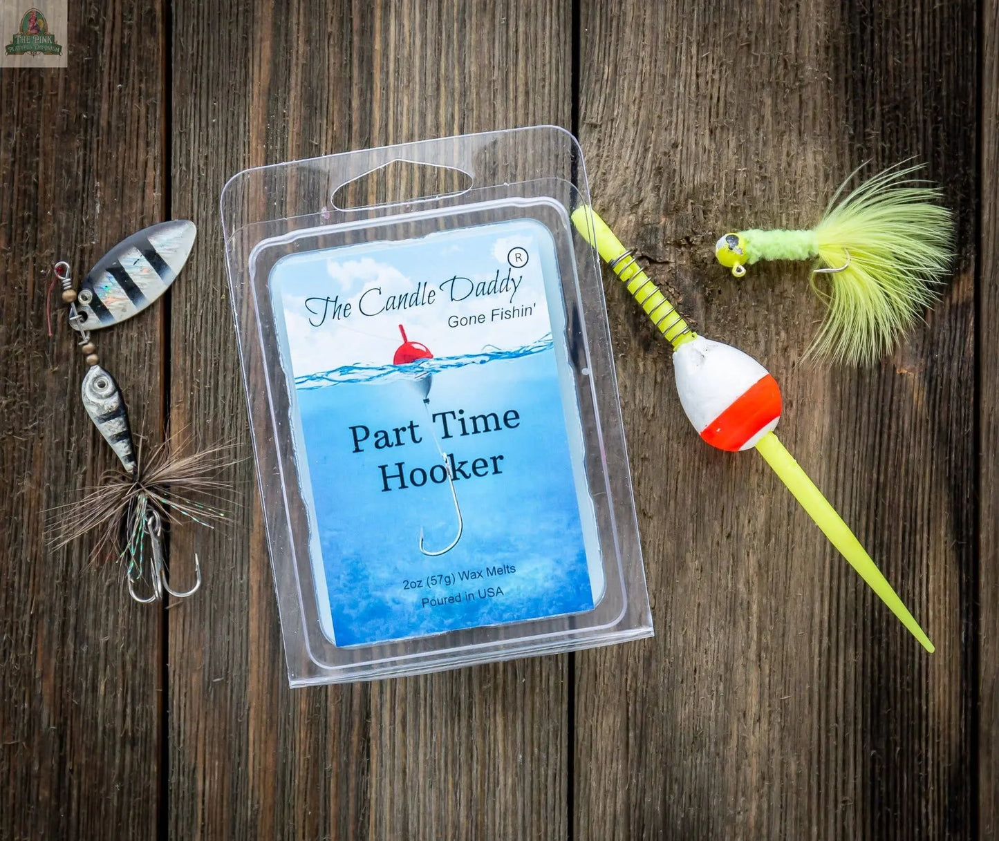 A package of The Candle Daddy's Gone Fishin' - Part Time Hooker scented wax cubes sits on a wooden surface, surrounded by fishing lures, a bobber, and tackle.