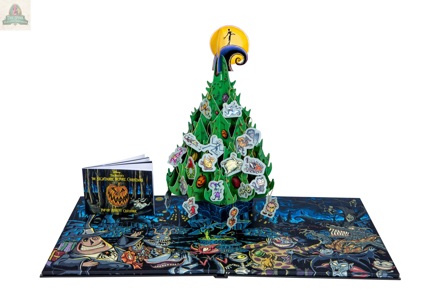 The Nightmare Before Christmas: Advent Calendar & Pop-Up Book features a 3D green pop-up tree, character tokens, a small illustrated book, and a colorful game board with spooky artwork inspired by Tim Burton’s film.