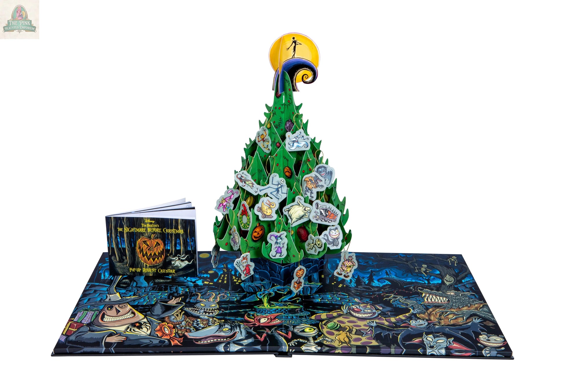 The Nightmare Before Christmas: Advent Calendar & Pop-Up Book features a 3D green pop-up tree, character tokens, a small illustrated book, and a colorful game board with spooky artwork inspired by Tim Burton’s film.