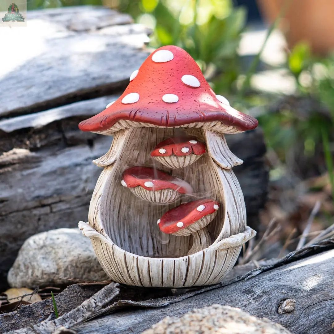 The Toadstool Mushroom Backflow Waterfall Incense Burner, crafted from cold cast resin, showcases three floating red-capped mushrooms inside its red-and-white spotted cap—ideal for outdoor display among rocks, wood, or greenery.