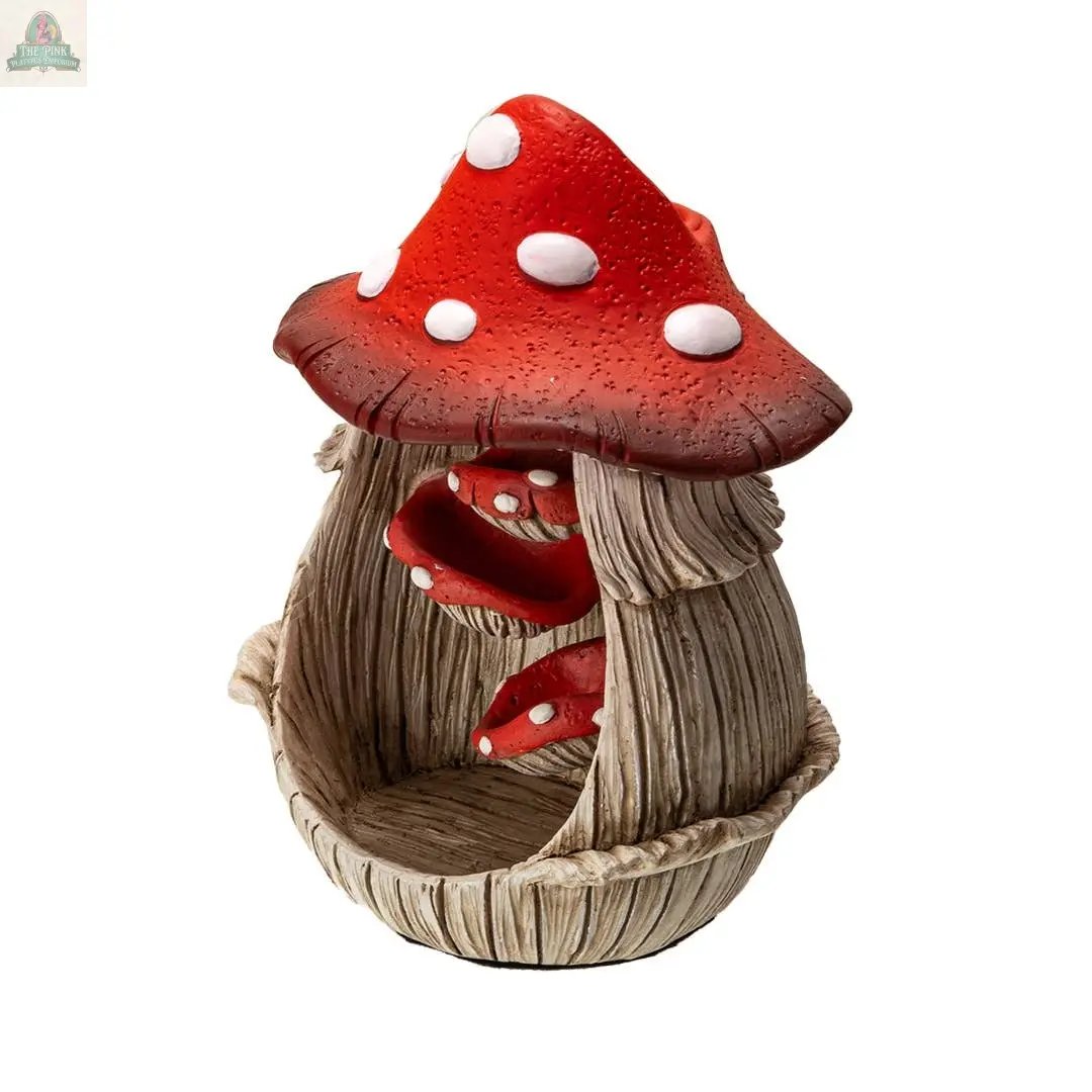 The Toadstool Mushroom Backflow Waterfall Incense Burner features a red and white spotted house-shaped design with a wood-textured hollow interior. Smaller red mushrooms inside create a magical backflow waterfall effect when incense is burned.