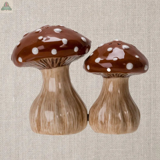 The Toadstool Mushrooms Salt and Pepper Shaker Set features two brown shakers with white spots, shaped like mushrooms and displayed on a textured beige background—an adorable addition to any kitchen décor.