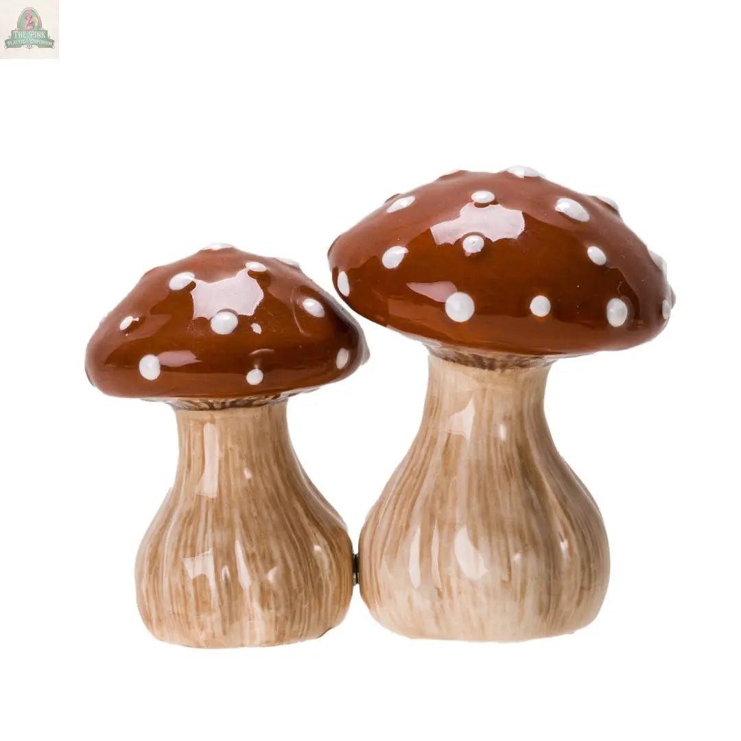 The Toadstool Mushrooms Salt and Pepper Shaker Set includes two ceramic shakers with brown caps, white spots, and beige stems, ideal for kitchen décor. They stand side by side on a white background.