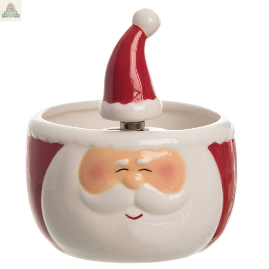 The Transpac Dol Santa Bowl w/Spreader S/2 is a festive ceramic bowl shaped like Santa's smiling face, complete with a red hat handle. Ideal for Christmas décor, it features rosy cheeks and closed eyes—perfect for the holiday season.