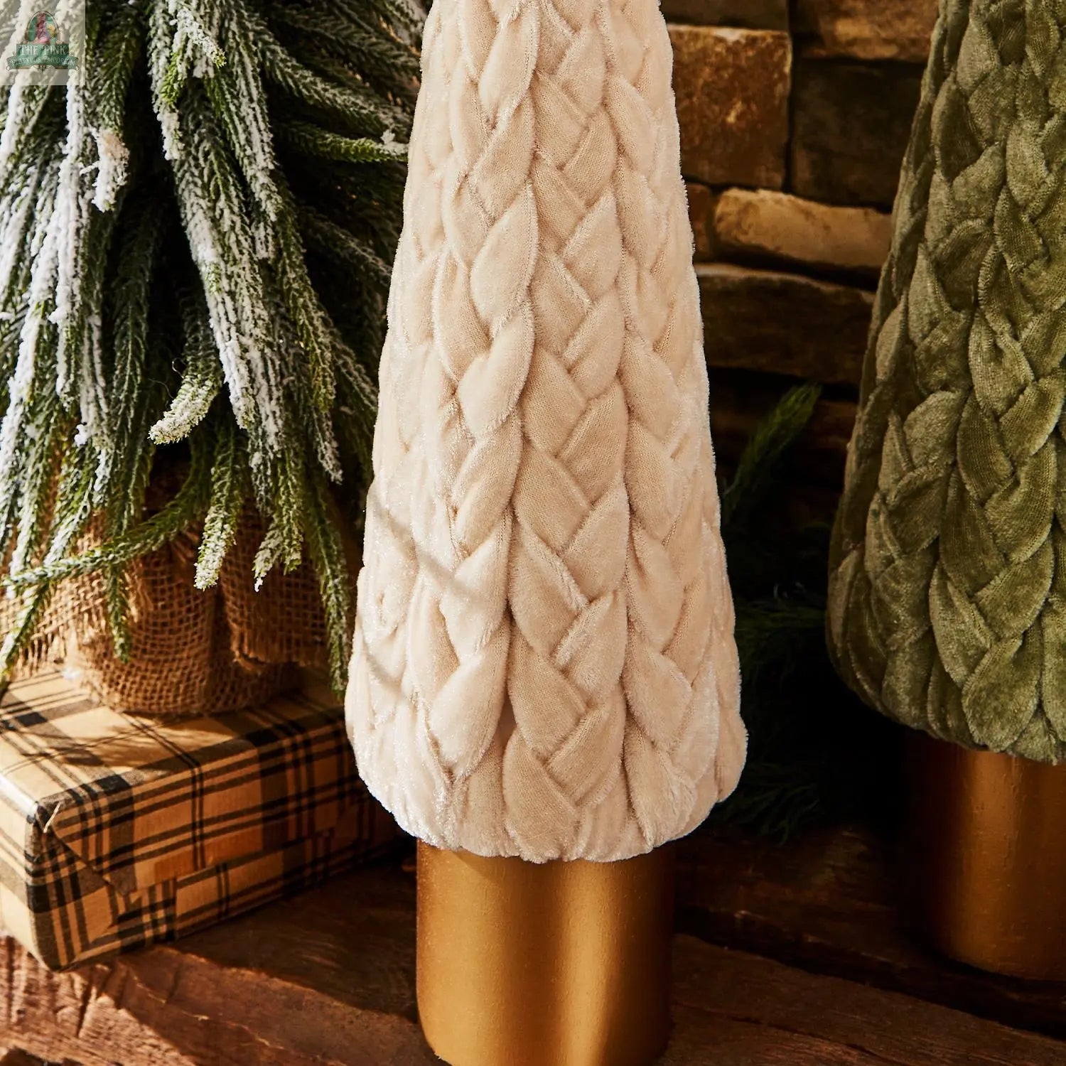 The Velvet Christmas Tree, in plush cream velvet with a braided texture and gold base, pairs with a green velvet tree and a gift to add cozy farmhouse style to your holiday decor, set against a rustic wood and stone backdrop.