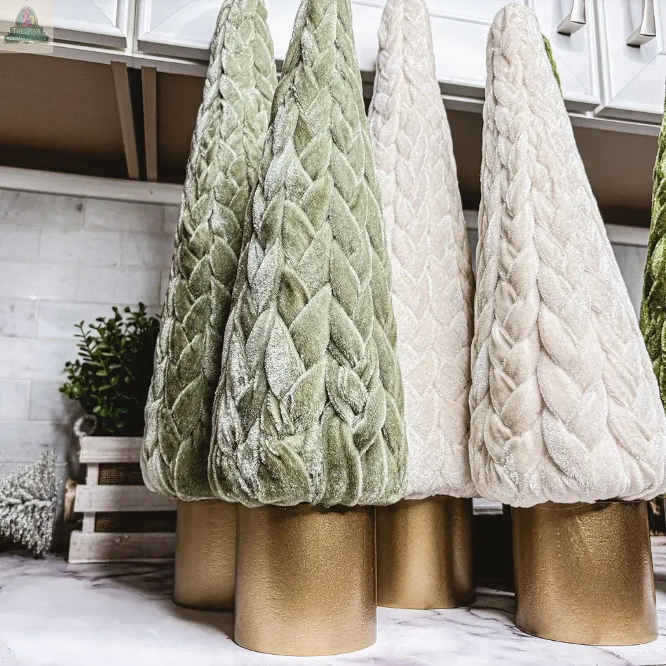 Velvet Christmas Trees in pale green and cream feature plush quilted fabric and stand on gold bases, arranged on marble with a tiled background—perfect for charming holiday decor.