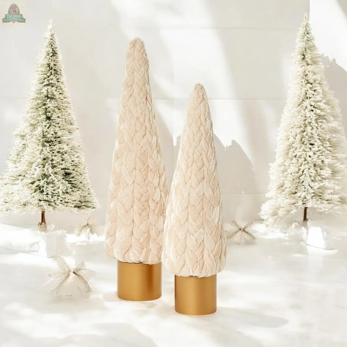 Two plush, cream-colored Velvet Christmas Trees with gold bases stand before snowy artificial trees on a glossy white floor, creating a minimal winter holiday décor scene ideal for Christmas mantel decorations.