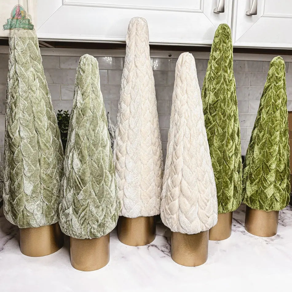 Six Velvet Christmas Trees in green and cream, each with a gold cylindrical base, stand on a marble countertop, bringing chic holiday décor to a modern kitchen.