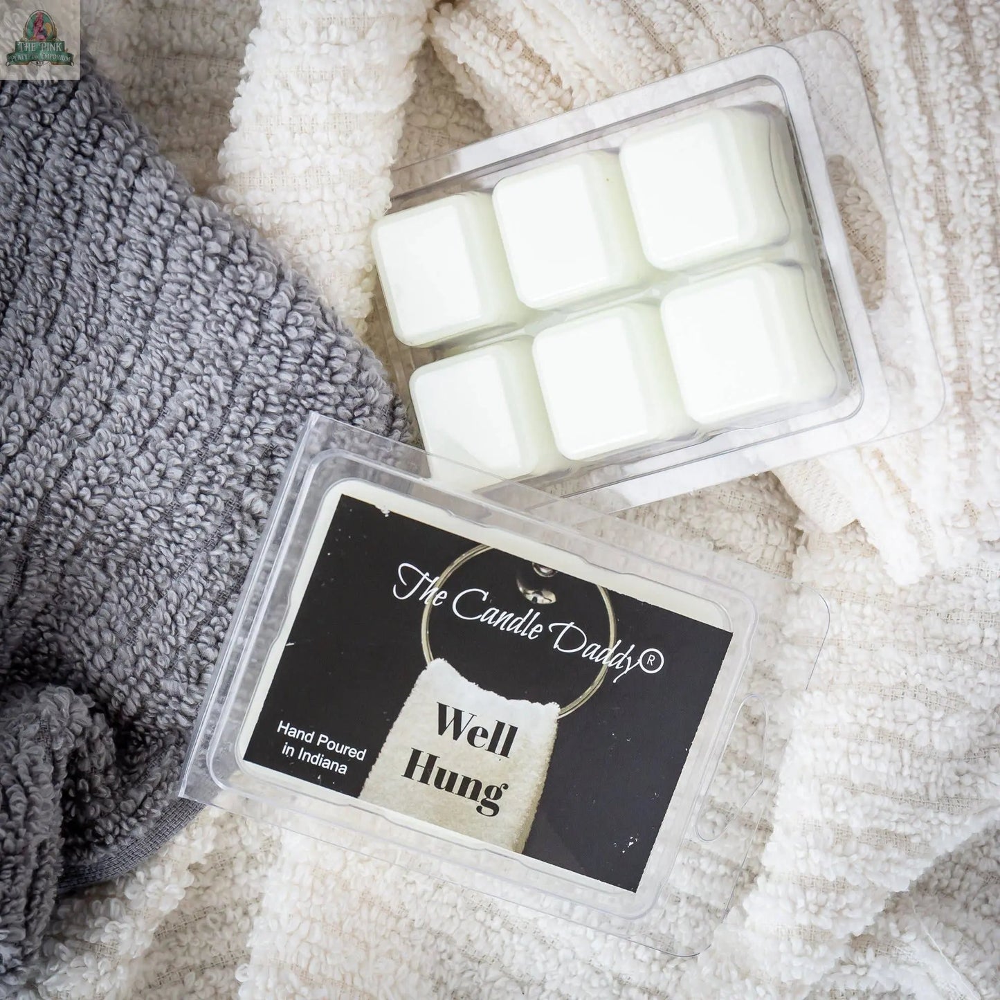 A pack of Well Hung - Fresh Linen Scented Wax Melts sits on gray and white towels. Nearby, another open pack of wax melts is ready to fill your space with a fresh linen aroma.