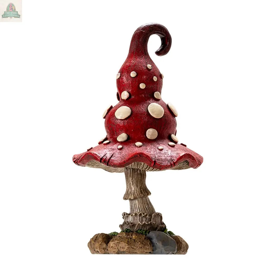 The Whimsical Toadstool Mushroom Home and Garden Decor features a charming red figurine with white spots, curled top, and textured stem on a soil-and-rock base—ideal cottagecore decor for mushroom lovers.