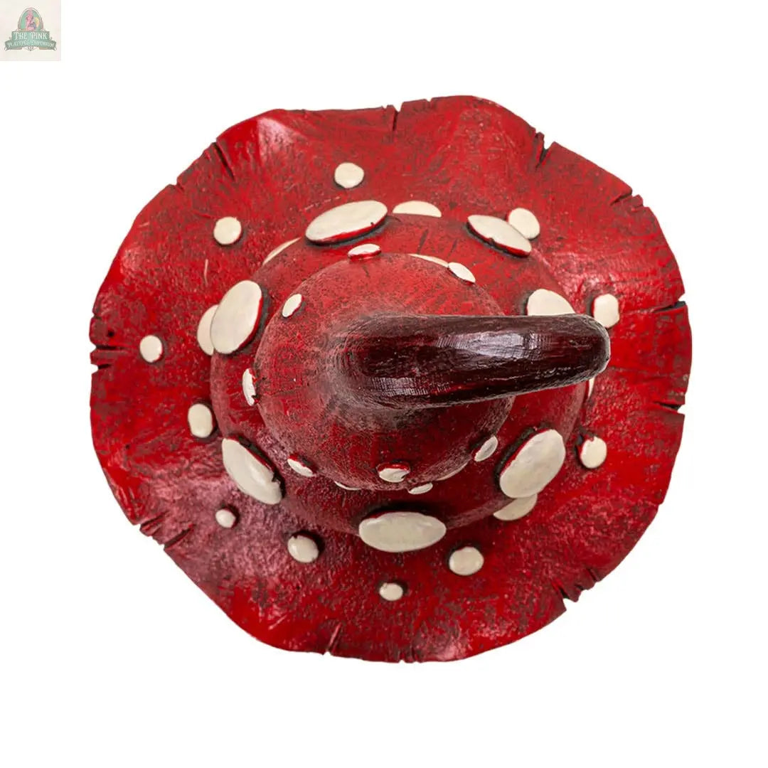 The Whimsical Toadstool Mushroom Home and Garden Decor is a red witch hat with a wide, wavy brim and white spots, featuring a shiny, textured surface that resembles a toadstool cap—perfect for cottagecore garden accents.