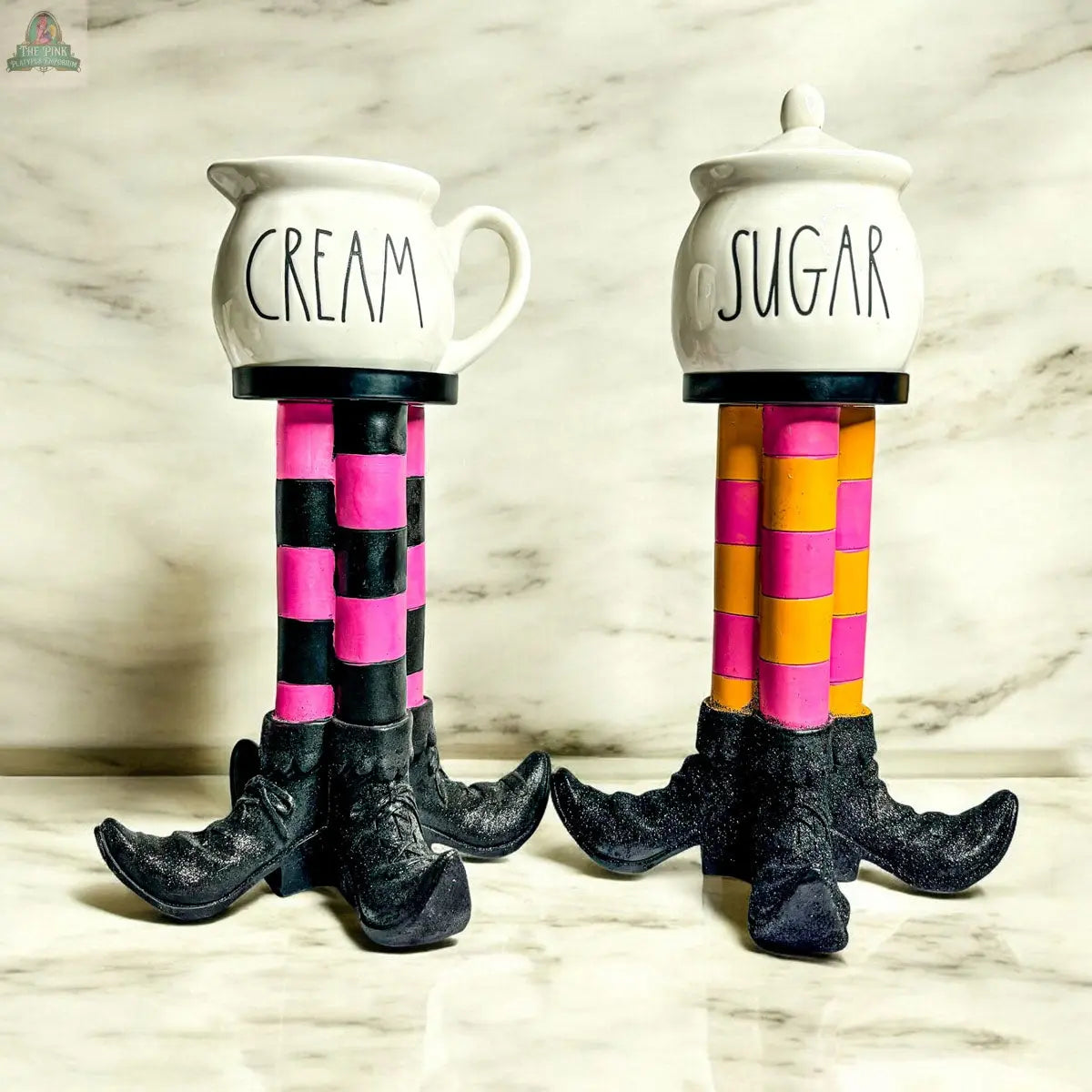The Wicked Witch Candle Holder features whimsical stands shaped like black witch legs with striped stockings, making a charming Halloween centerpiece and perfect touch of decor against a marble background.
