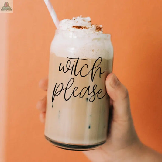 A hand holds the Witch Please 17oz glass cup filled with iced coffee, topped with whipped cream and a stainless steel straw. "Witch Please" is written in black cursive on the glass, set against a solid orange background.
