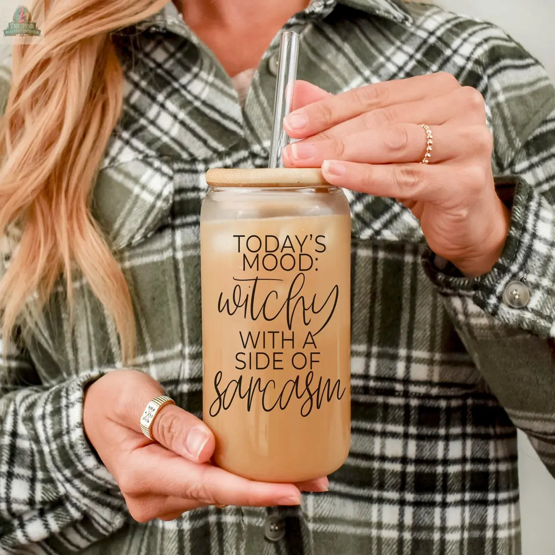 A person in a green plaid shirt holds the Witchy 20oz glass tumbler filled with iced coffee. The jar reads, "Today's mood: witchy with a side of sarcasm"—perfect as a unique witch gift.