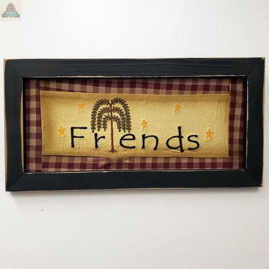The Wood Framed Friends Stitchery features a painted wood frame, red and tan plaid border, "Friends" stitched in black on yellow with a willow tree for the 'i', and yellow stars—perfect cozy decor for your home.