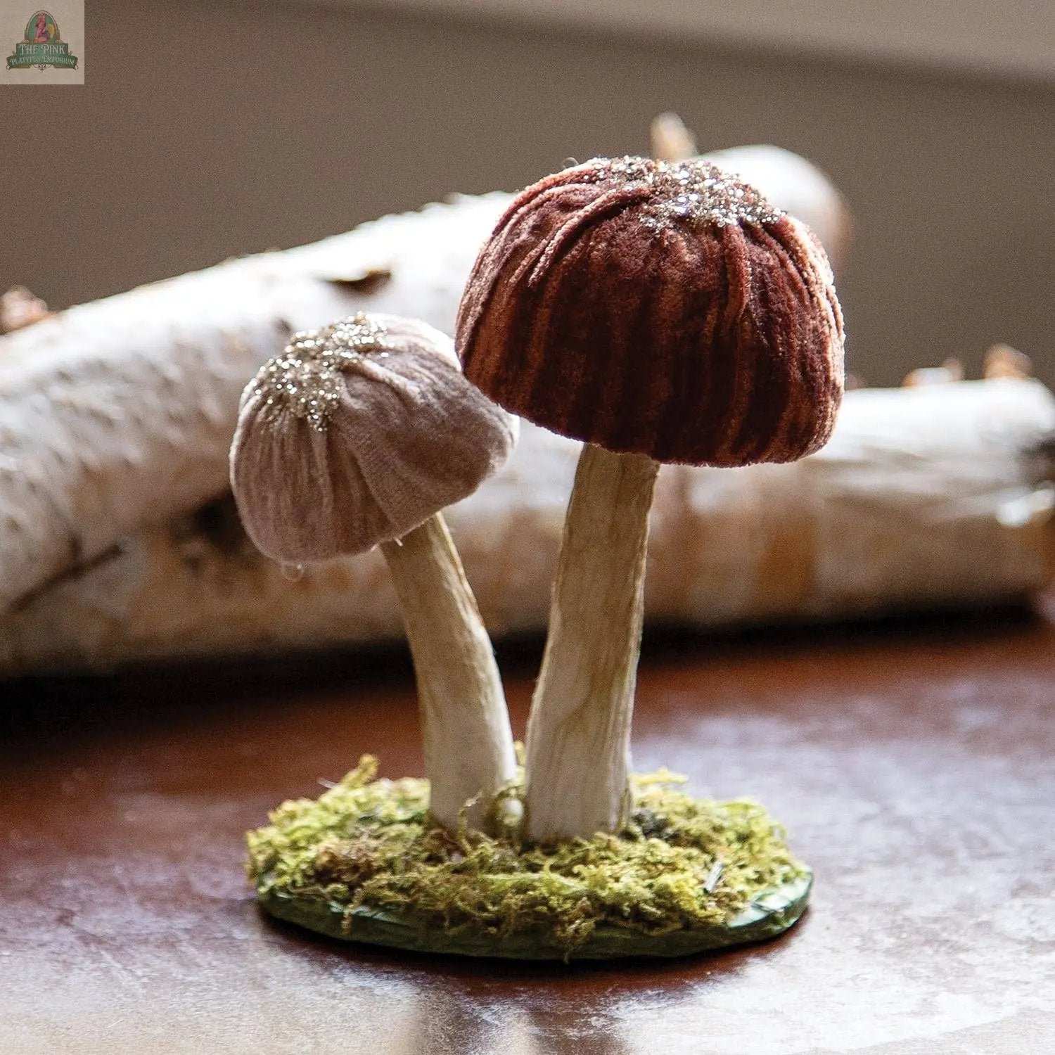 The Woodland Brown Mushrooms Sitter - Small features two fabric mushrooms—one brown, one tan—with textured caps on a mossy base, perfect as charming woodland decor for your winter forest display. A birch log is softly blurred in the background.