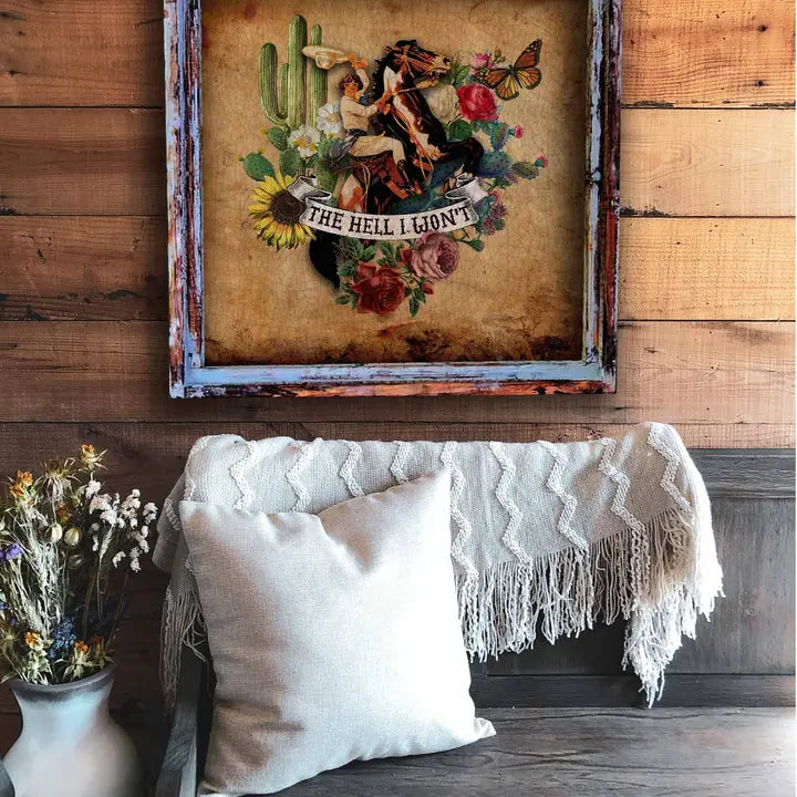 Decorative wall art with floral and cactus design above a couch with pillows and a blanket.