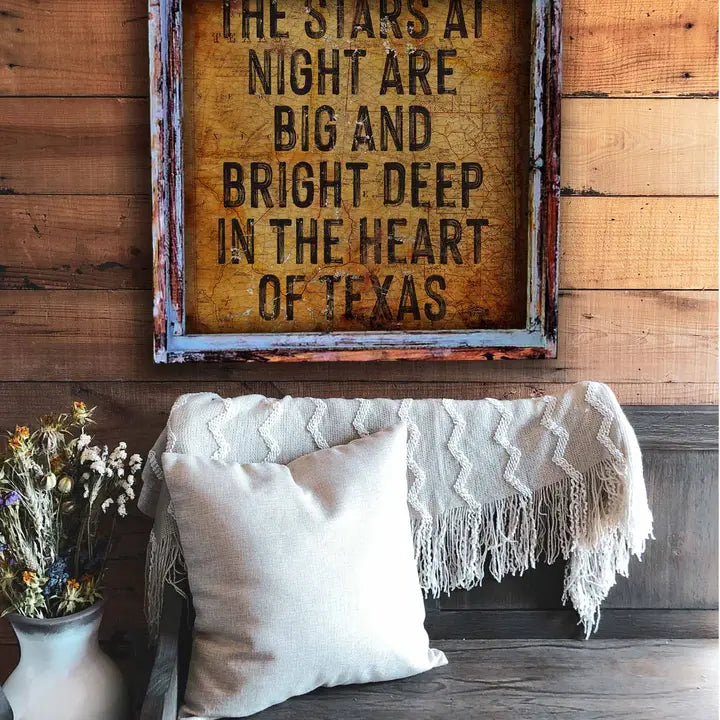 Decorative sign with text on a wooden wall above a couch with pillows and a blanket.