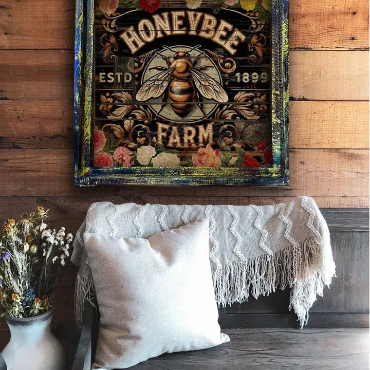 Decorative sign for 'Honeybee Farm' on a wooden wall above a couch with pillows and a blanket.