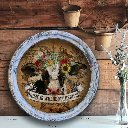 farmhouse wall decor with a cow illustration and 'Home is where my herd is' text on a wooden background.