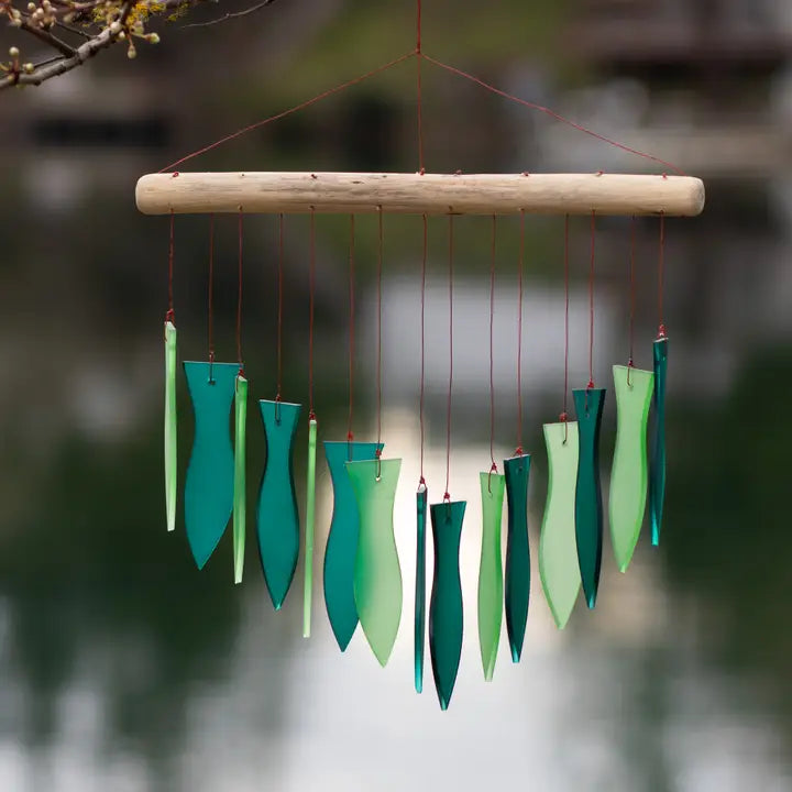 Decorative recycled glass wind chime with two different colors of green hanging against a blurred natural background