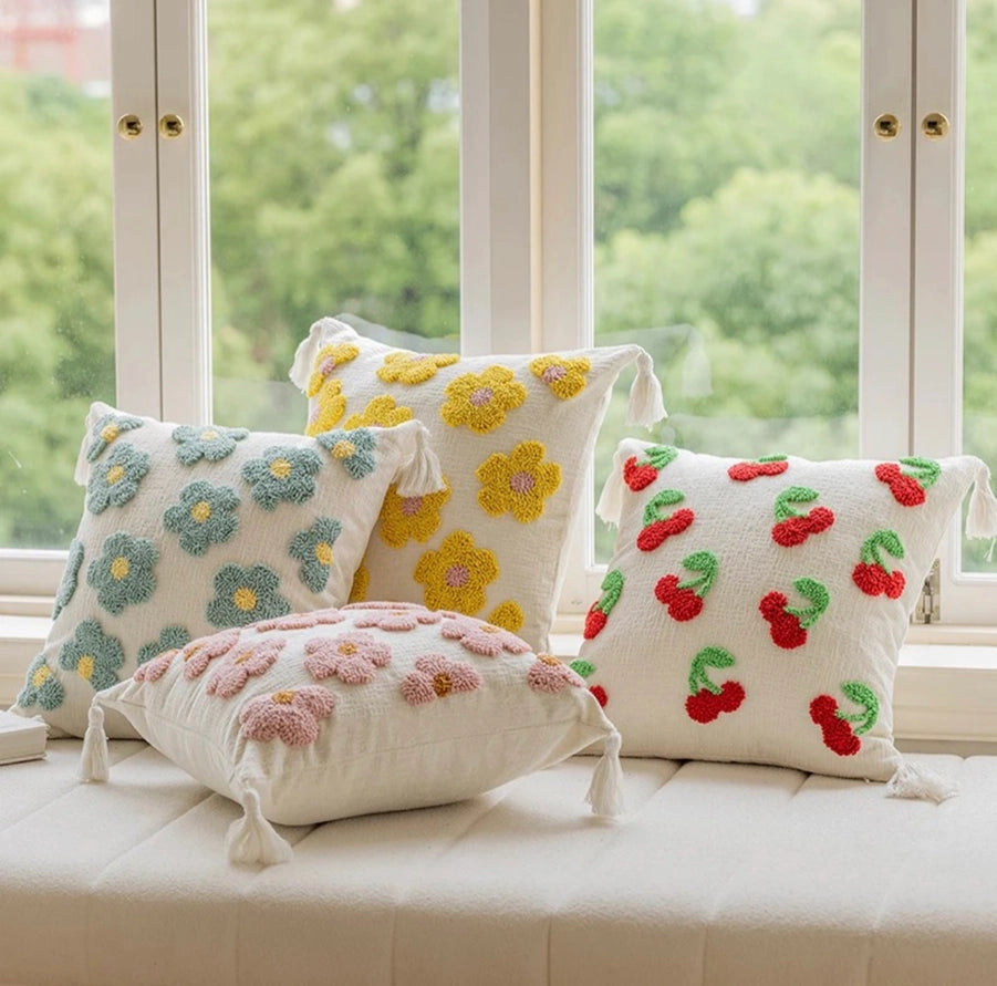 Decorative pillows with floral and cherry patterns on a window seat.