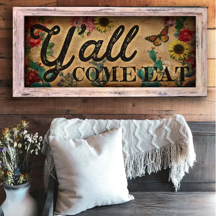 Kitchen wall art with 'Y'all Come Eat' text on a wooden wall above a couch.