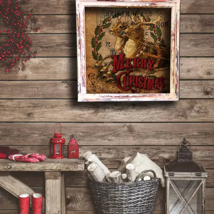 Framed Christmas-themed print on a wooden wall with decorative lanterns and boots.