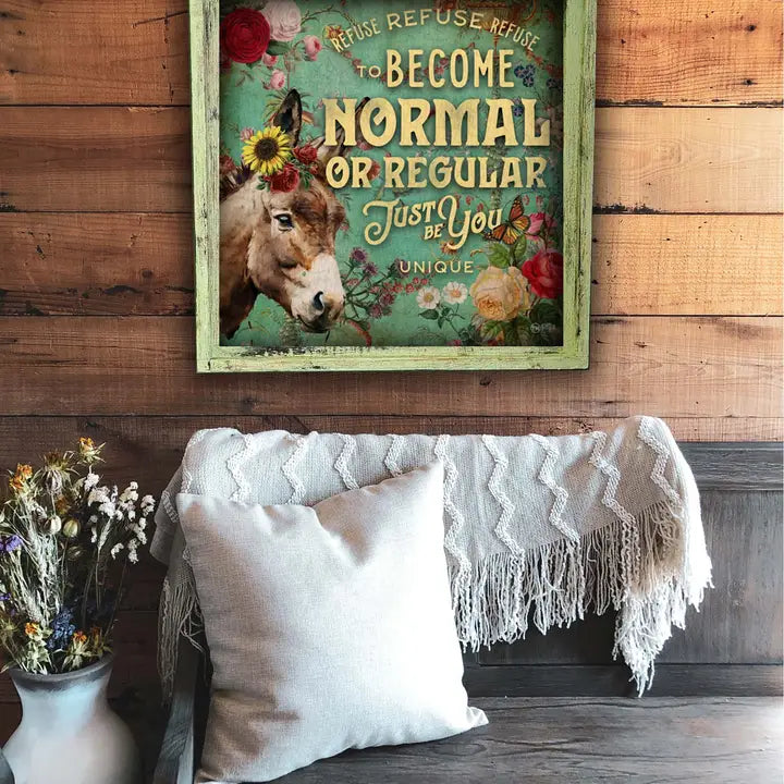 Decorative sign with a donkey and floral elements on a wooden wall above a sofa.