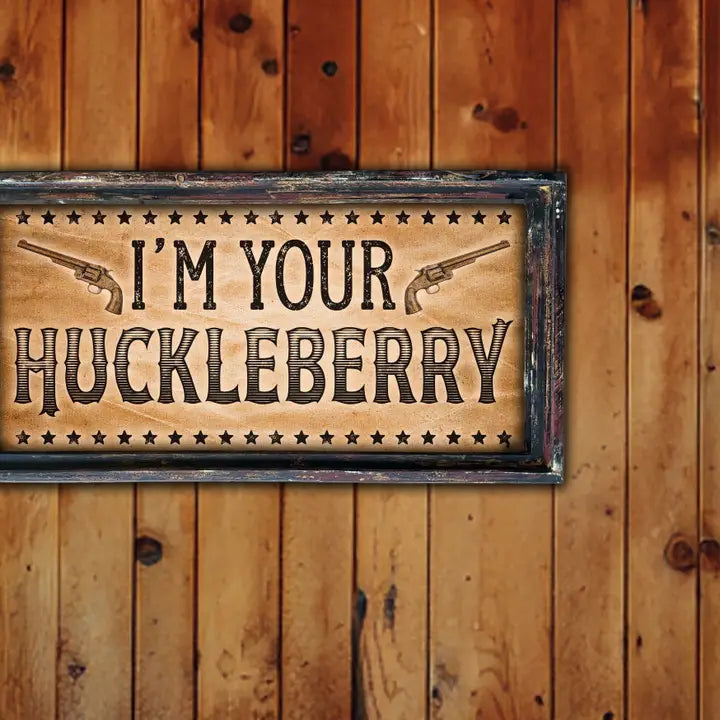 Vintage western art with 'I'm your Huckleberry' text and gun graphics on a wooden background