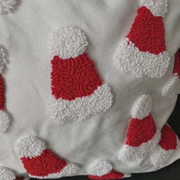 Close-up of red and white textured shapes resembling Santa hats on a white fabric background.