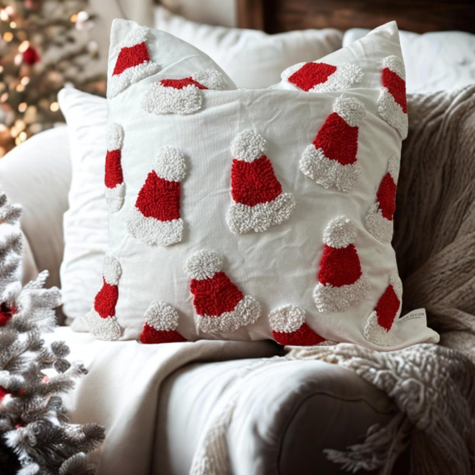 Decorative pillows with red and white santa hats on a couch with a Christmas tree in the background.