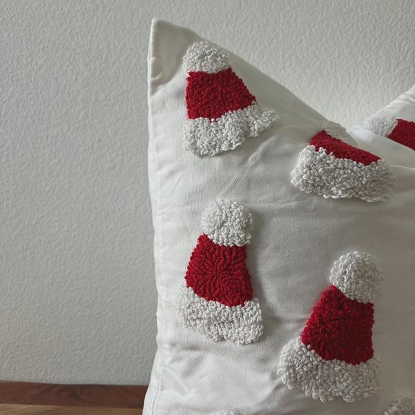 Decorative pillow with red and white textured santa hats on a plain background