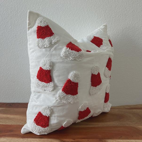 Decorative pillow with red and white santa hats on a wooden surface
